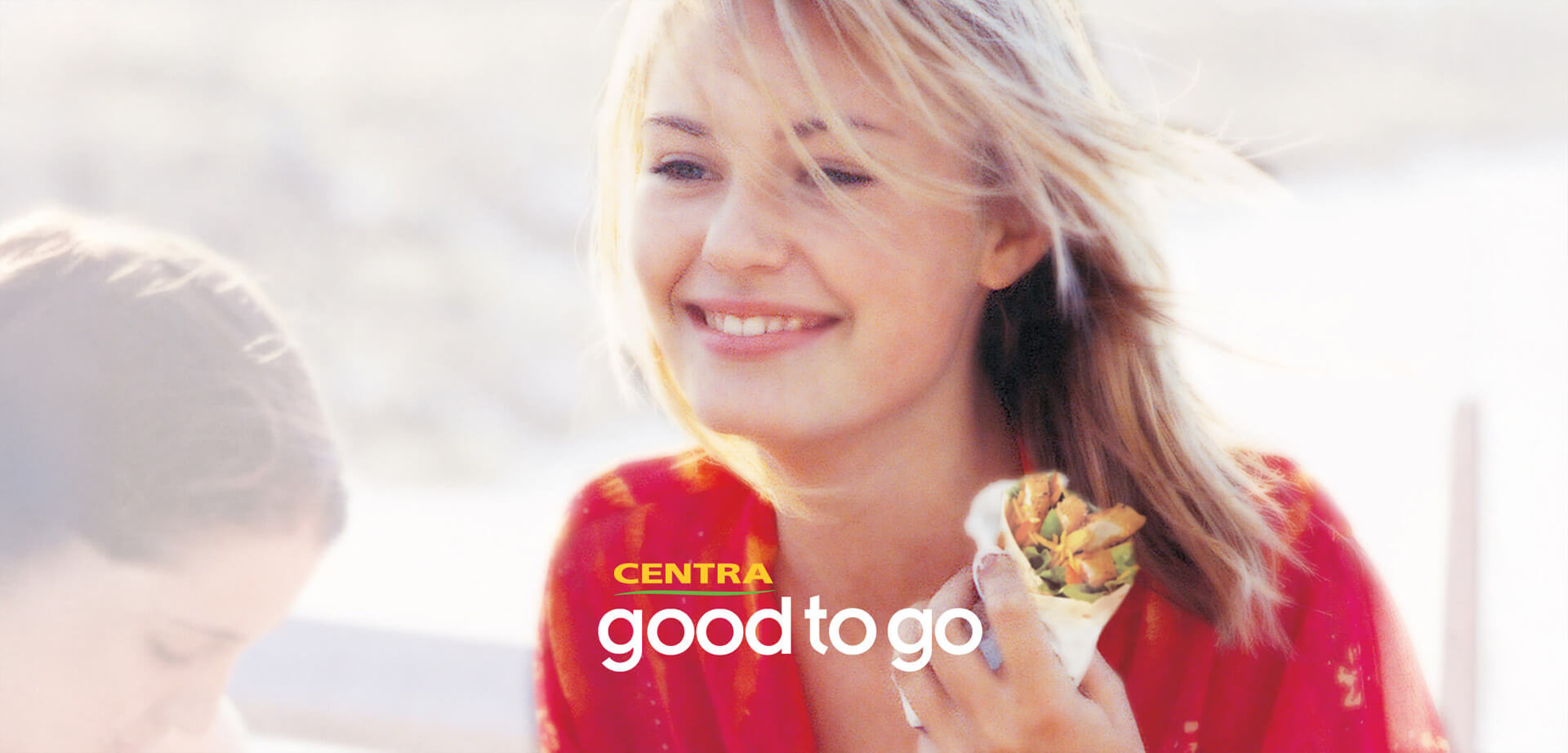 The image shows the exterior of a Centra convenience store, an Irish-based retailer, promoting their in-store food options. The store brand is "Centra". They offer a food service range with the slogan "hmmm... tasty". The food is marketed as "good to go" convenience items, including sandwiches, salads, and hot food options. 