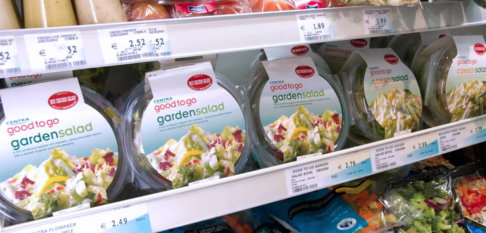 Centra "Good To Go" own label packaging design for garden salads on a supermarket shelf. The salads are packaged in clear plastic bowls with a white and green label. 