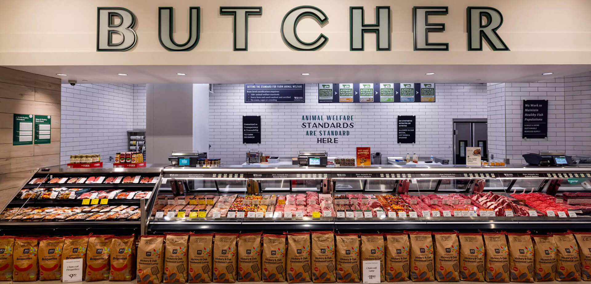 Whole Foods Market butcher counter. Overhead signage highlights the store's "Animal Welfare Standards". 