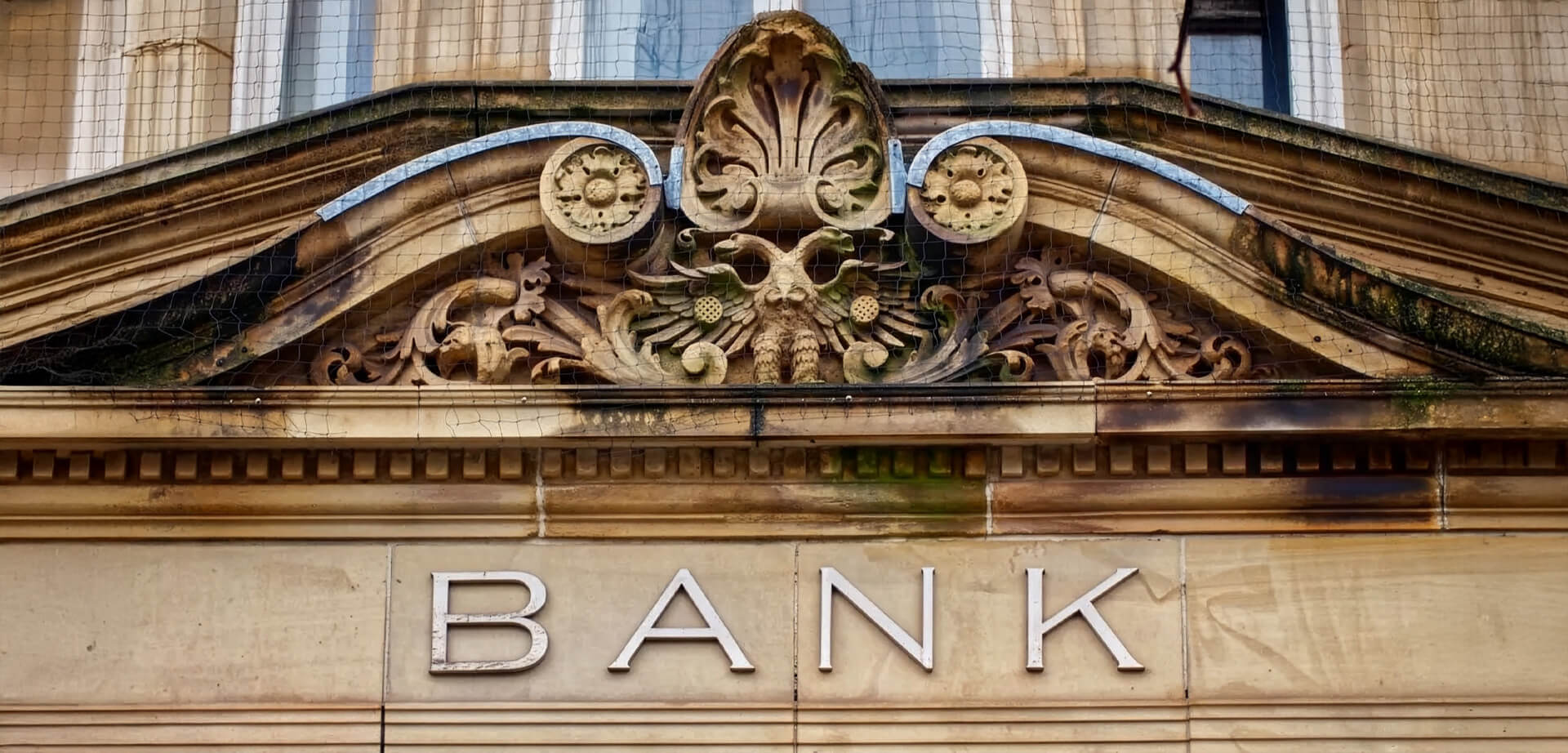 This image features a bank building entrance, characterized by traditional stone architecture and an ornate pediment.