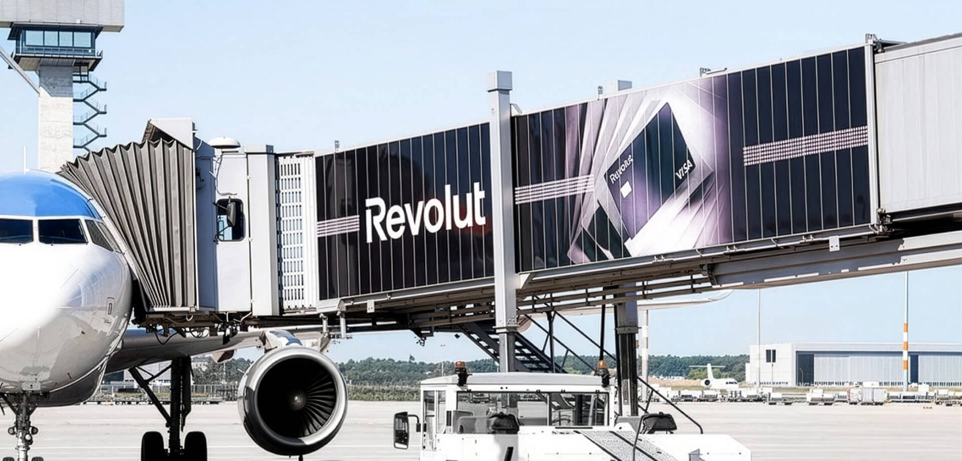This image shows prominent advertising for the fintech company Revolut placed on a passenger boarding bridge at an airport.     Revolut is a digital banking app and payment platform offering travel-related financial services like currency exchange. 