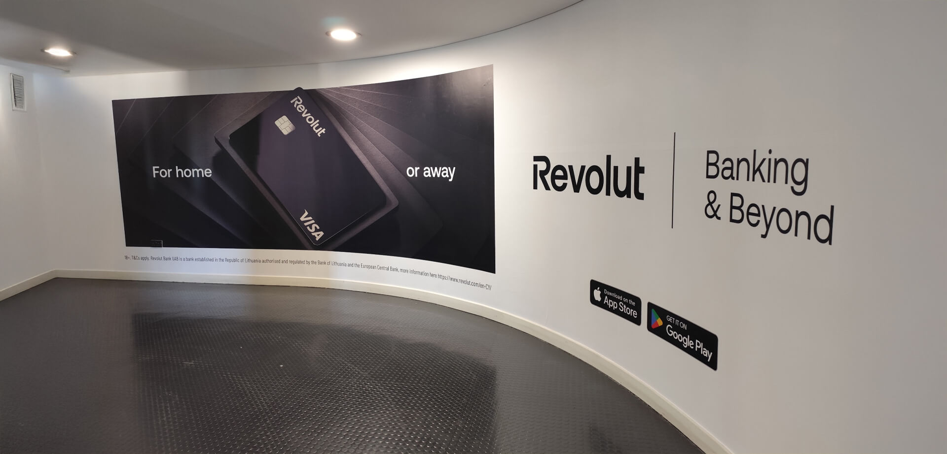 This image shows a marketing display for Revolut banking services in an airport walkway, highlighting their financial products for domestic and international use. 