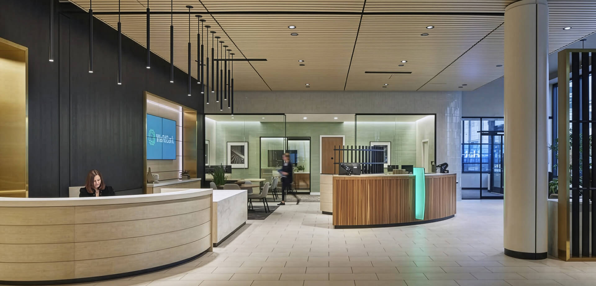 This modern bank interior features a curved, light-wood reception desk and an adjoining digital banking area, all designed with a community-first approach.