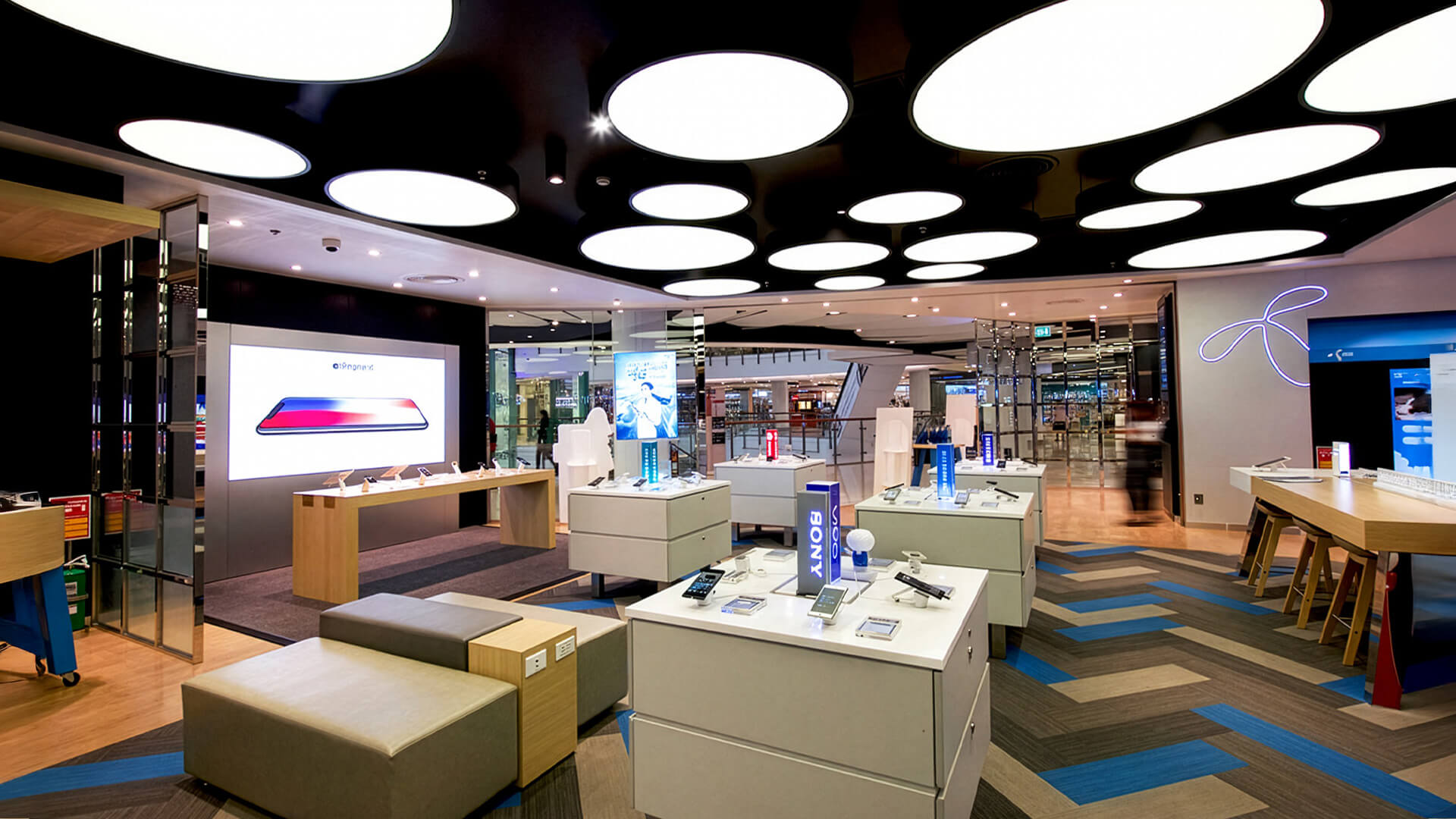 dtac dInfinite flagship. The space features a modern "endless digital experiences" theme characterized by circular ceiling lighting panels and modular, tech-integrated consultation tables.