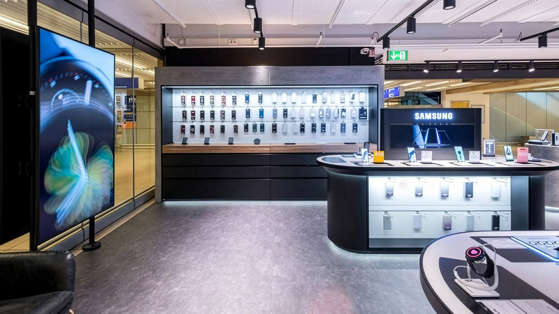 This is a view inside a modern Samsung Experience Store, which typically showcases the brand's latest Galaxy smartphones, tablets, smartwatches, and wireless earbuds.