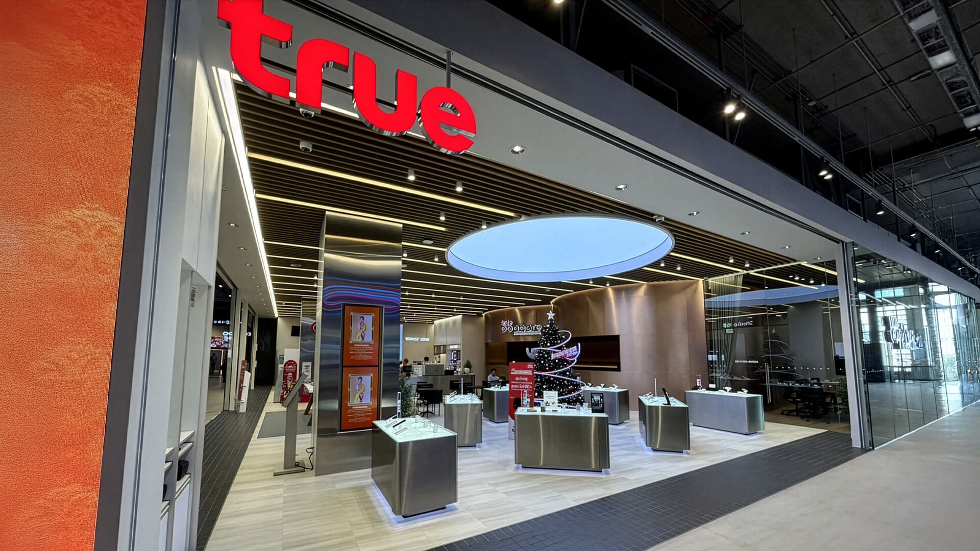 This image features the modern storefront of a True Shop, a prominent telecommunications and digital services provider in Thailand.Store Concept: This location showcases the brand’s "Future Retail" design.