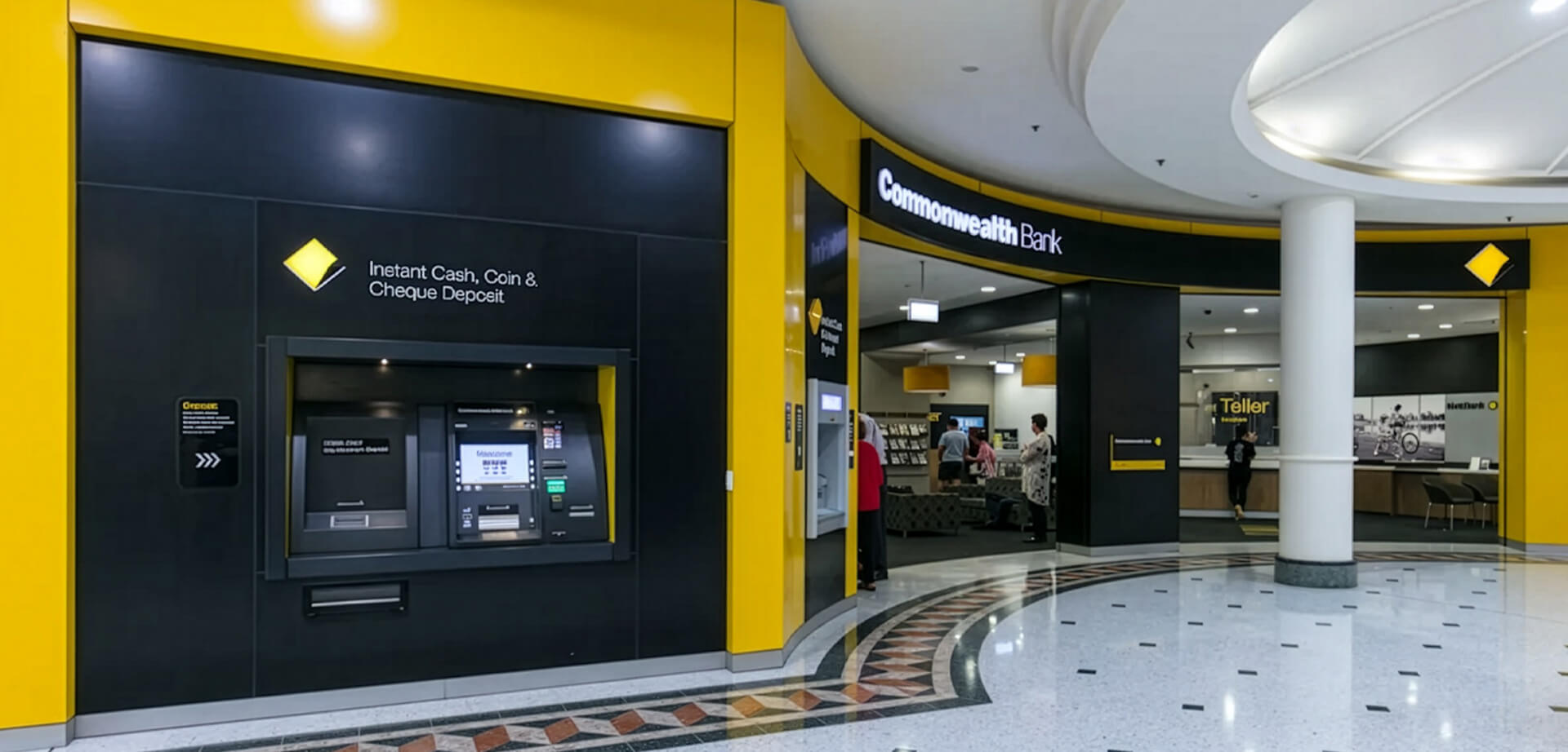 A modern, yellow-and-black branch of the Commonwealth Bank of Australia (CBA), showcasing both an indoor teller counter and outdoor smart ATMs.