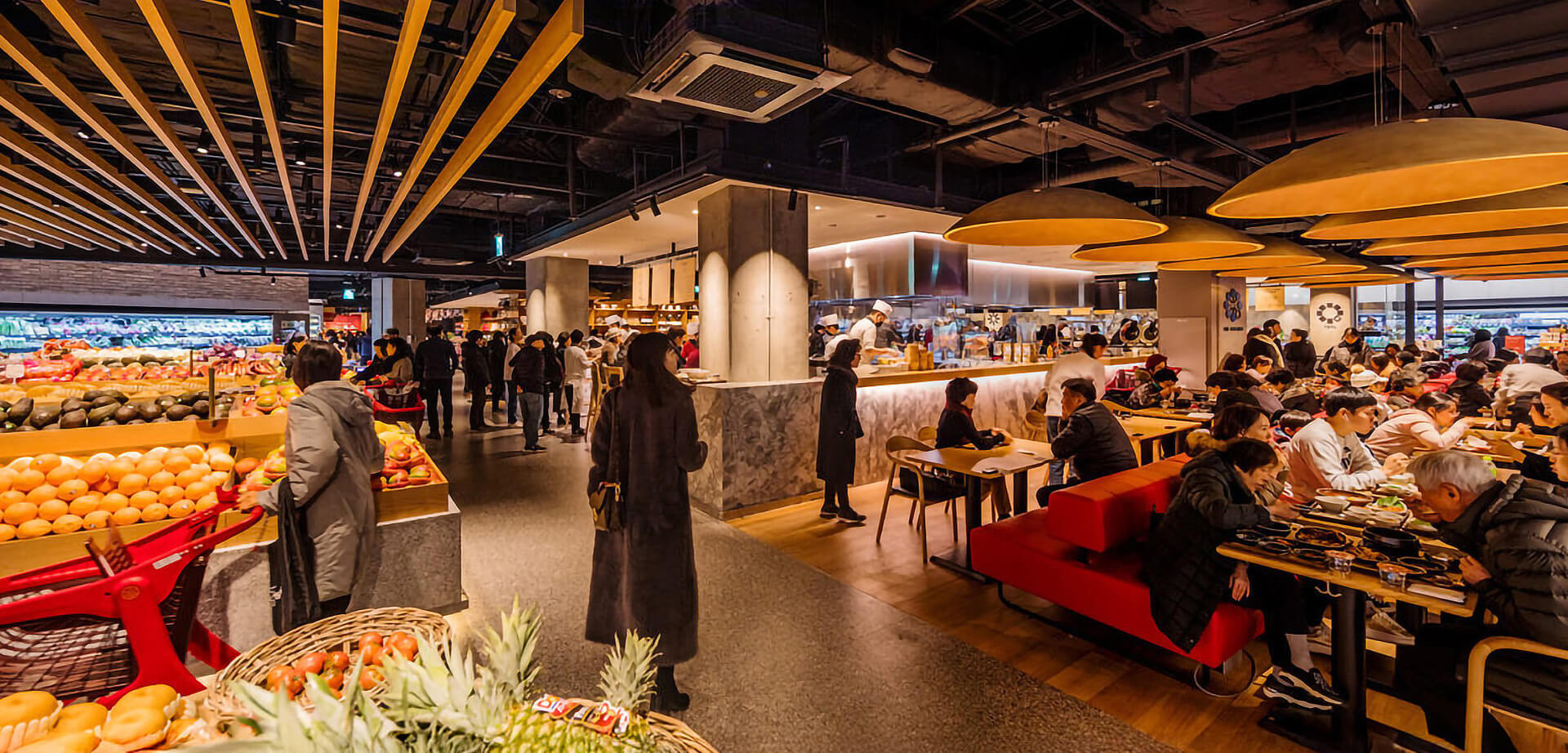 The image shows the interior of the SSG Food Market in Cheongdam, Seoul (now part of the House of Shinsegae). It features a modern, high-end grocery area with fresh produce displays on the left and a bustling dining and food hall section on the right.