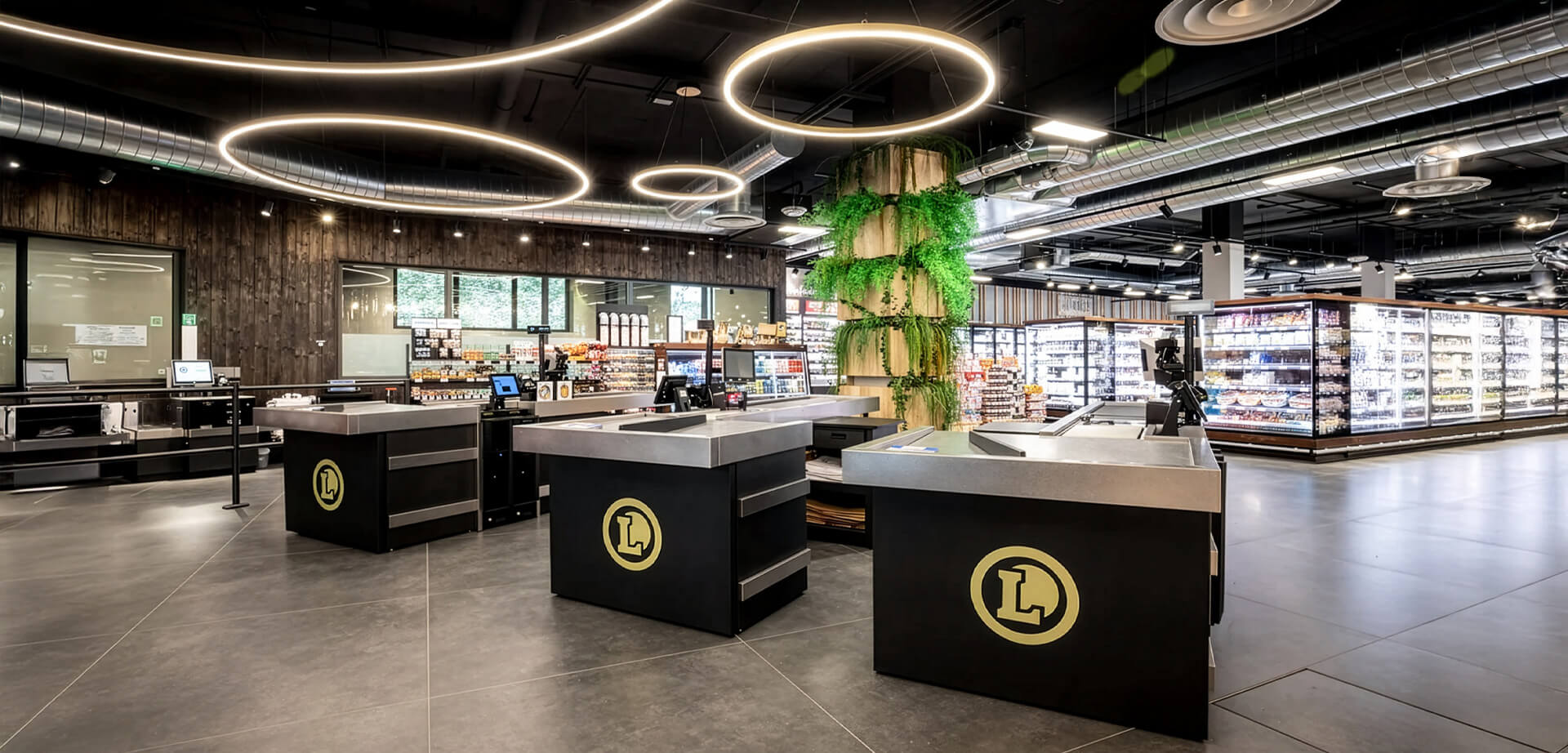E. Leclerc supermarket, characterised by sleek black counters with circular "L" logos, industrial-style exposed ductwork, and ring-shaped pendant lighting.