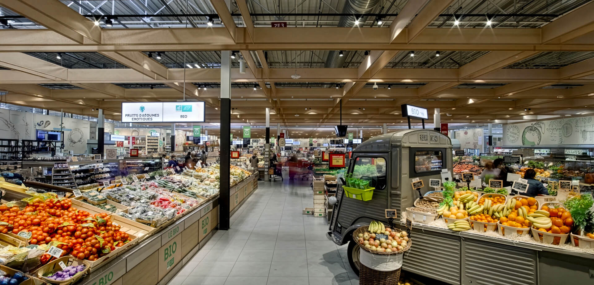 Carrefour's thematic displays: A defining feature of Grand Frais stores is their eye-catching visual merchandising, including the use of vintage vehicles (such as the classic Citroën HY van in the background) to display crates of fruits and vegetables.