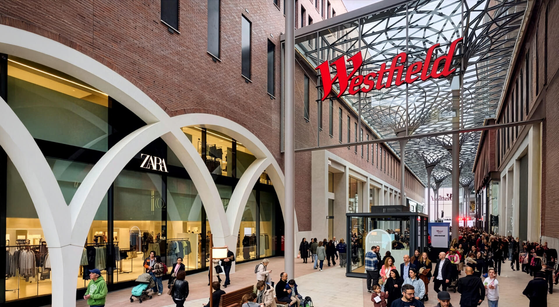 Westfield Hamburg-Überseequartier shopping district in Germany, featuring a large Zara store on the left and a sweeping net-like glass canopy roof.