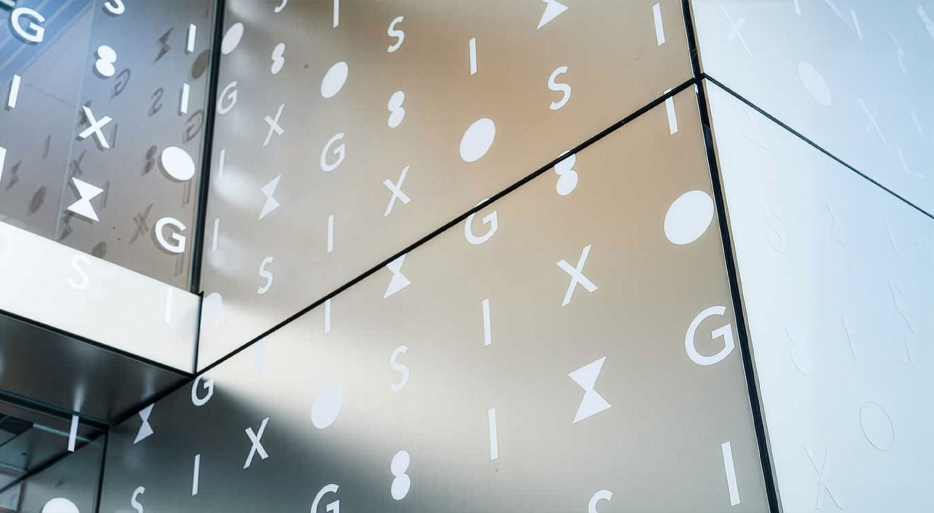 The metallic exterior facade of GINZA SIX in Tokyo, featuring a patterned design of the letters G and S, along with I and X and circular motifs