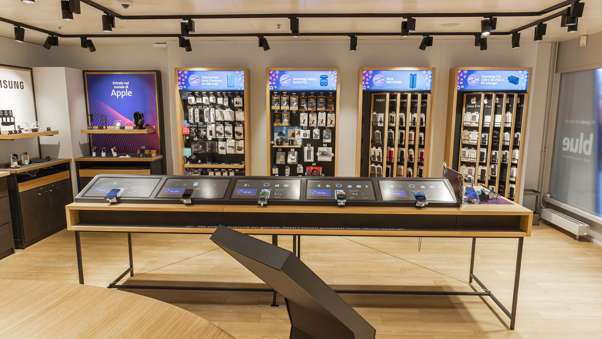 The image shows the interior of a modern Swisscom telecommunications store, specifically highlighting a custom interactive retail display island along with dedicated wall-mounted promotional bays.