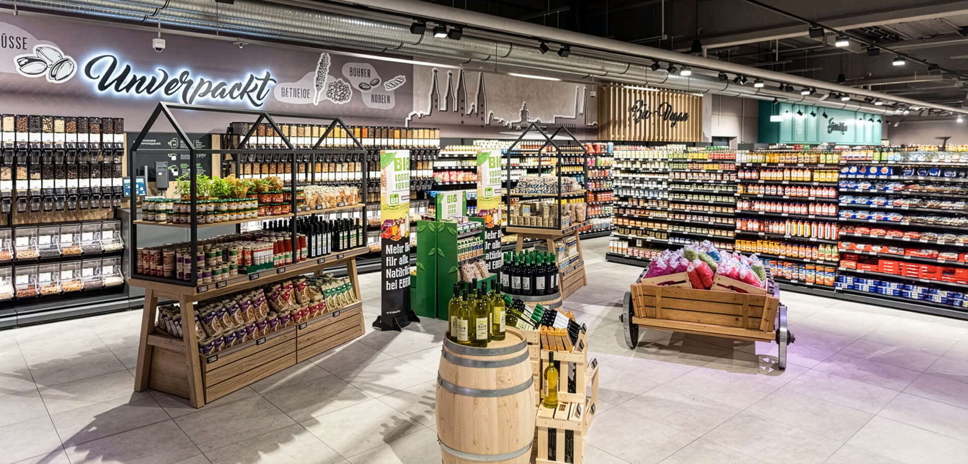 The image shows the unpackaged ("Unverpackt") and organic sections inside the Edeka Massak E-Center in Bamberg, Germany, featuring wooden display fixtures and bulk food dispensers.