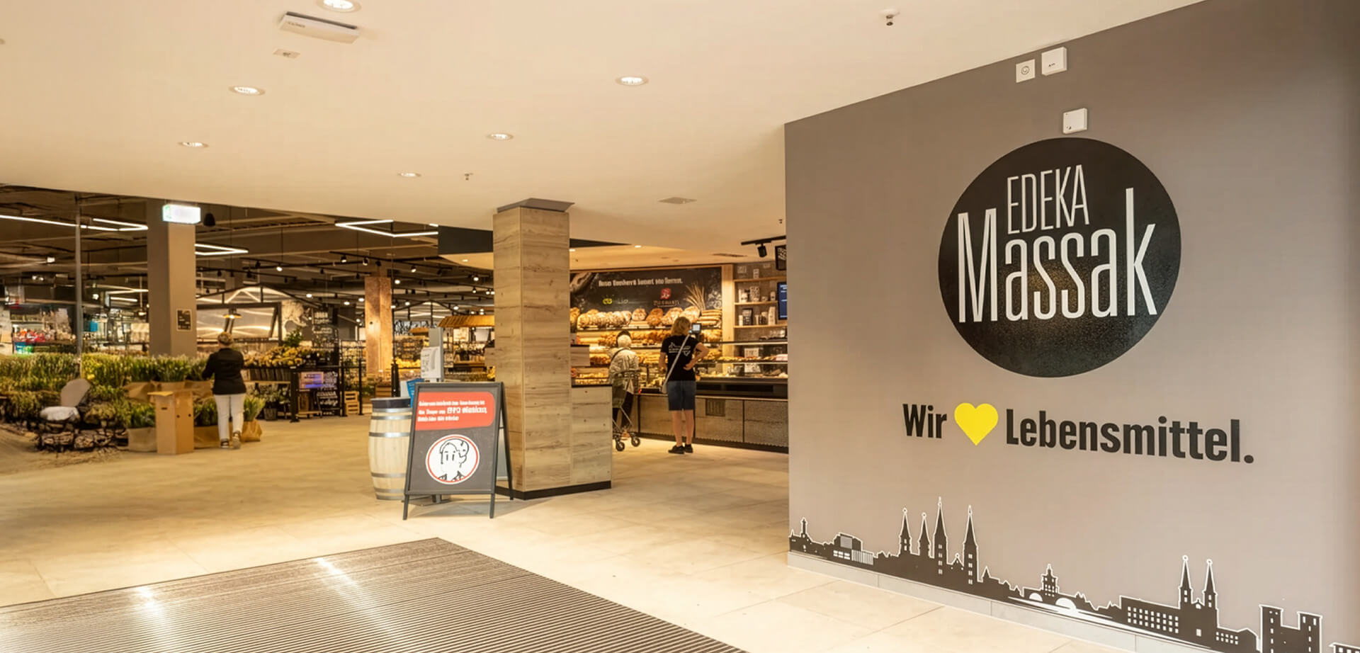 The interior entrance and signage of Edeka Massak, a modern supermarket located in Bamberg, Germany.