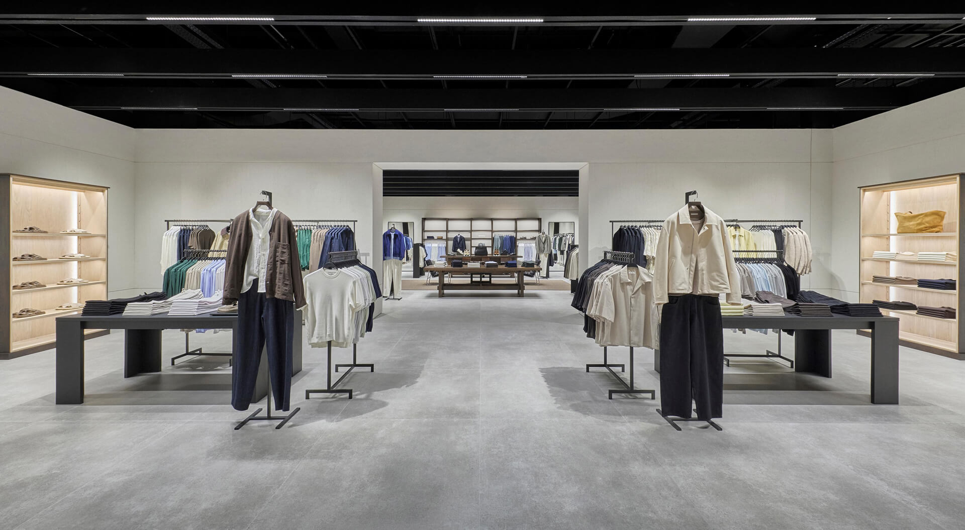 The Zara Trafford Centre store features a minimalist design with clean architectural lines, grey tiled floors, and wooden wall accents displaying curated menswear collections