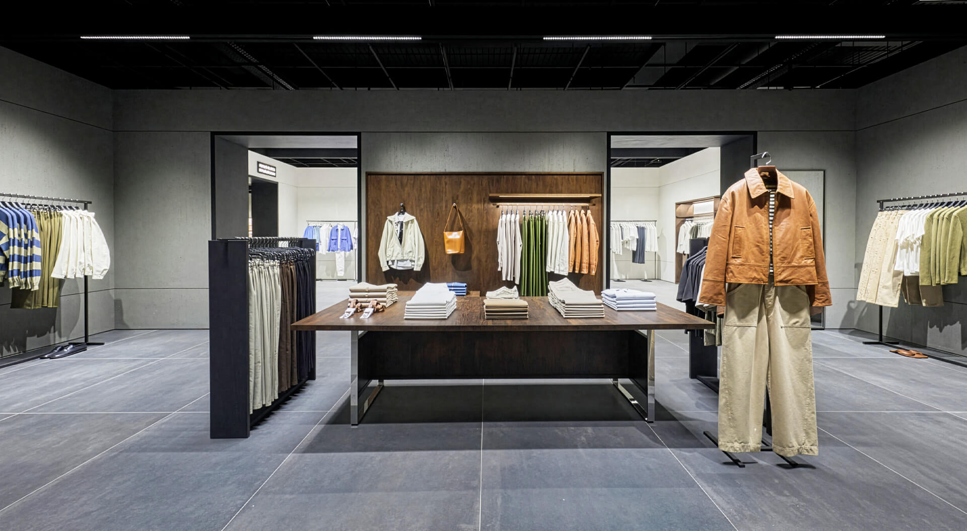 The Zara Trafford Centre store features a minimalist design with clean architectural lines, grey tiled floors, and wooden wall accents displaying curated menswear collections